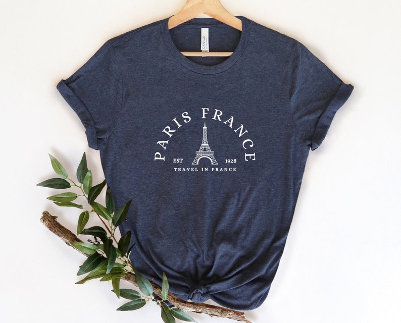 May include: A navy blue t-shirt with a white graphic of the Eiffel Tower and the text "Paris France Est 1928 Travel in France".
