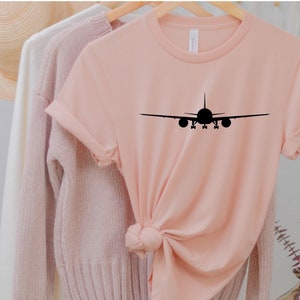 May include: A pink t-shirt with a black silhouette of an aeroplane on the front.