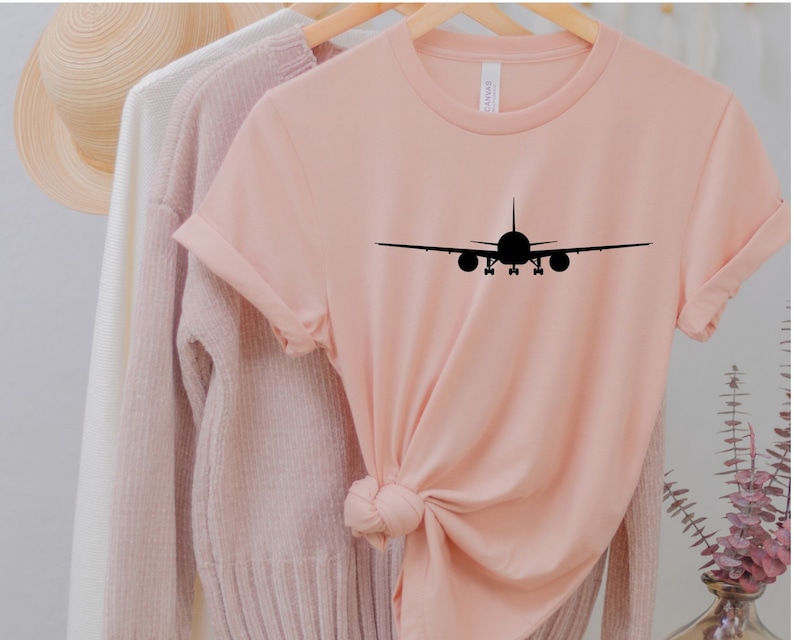 May include: A pink t-shirt with a black silhouette of an aeroplane on the front.