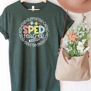 Pode incluir: Camiseta verde com um design circular que diz "SPED teacher" com as palavras "dedicado, gentil, solid&aacute;rio, atencioso, motivador, confi&aacute;vel e planejador" ao redor do c&iacute;rculo.