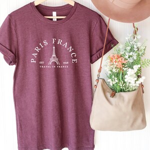 May include: Burgundy t-shirt with a white graphic of the Eiffel Tower and the text "Paris France Est. 1928 Travel in France".
