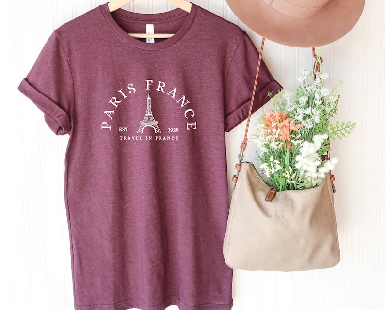 May include: Burgundy t-shirt with a white graphic of the Eiffel Tower and the text "Paris France Est. 1928 Travel in France".