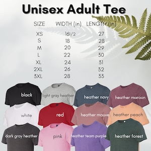 May include: Unisex adult t-shirt size chart with measurements in inches. The chart shows the width and length of the shirt in inches for sizes XS to 3XL. The chart is displayed against a background of a fern leaf. Below the chart are 10 t-shirts in different colours, including black, white, light grey heather, red, pink, heather navy, heather maroon, heather mauve, heather peach, heather team purple, and heather forest.