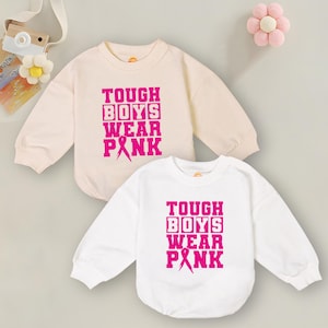 May include: Two long-sleeved shirts with the text "TOUGH BOYS WEAR PINK" in pink letters. The shirts are white and light pink.