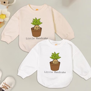 May include: Two long-sleeved shirts with a cartoon illustration of a mandrake plant in a pot. The text "Little Mandrake" is printed on both shirts.