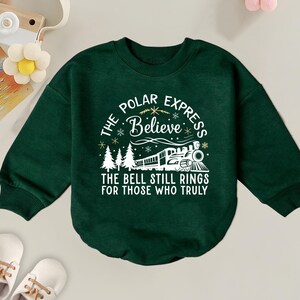 May include: Green long-sleeved sweatshirt with a white graphic of a train and the text "The Polar Express Believe The Bell Still Rings For Those Who Truly".