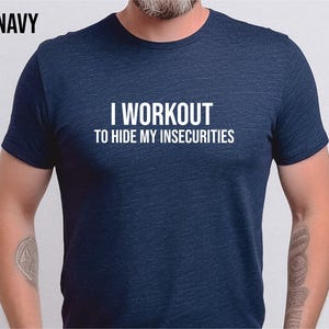 Puede incluir: Una camiseta azul marino con el texto "I workout to hide my insecurities" impreso en blanco.