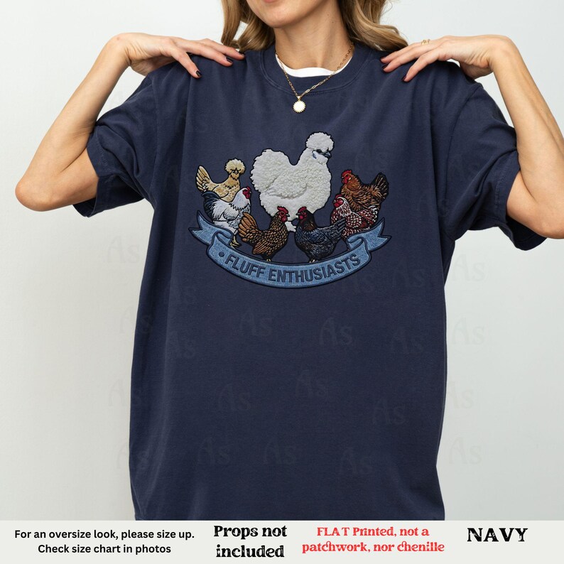 Pode incluir: Camiseta azul marinho com um gr&aacute;fico de v&aacute;rias galinhas e o texto "FLUFF ENTHUSIASTS" em uma faixa azul. A camiseta &eacute; de cor azul marinho s&oacute;lida e tem gola redonda.