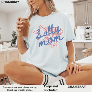 May include: A light blue t-shirt with the text "Salty Mom" in blue and red lettering. The text is surrounded by a starfish and seashells.
