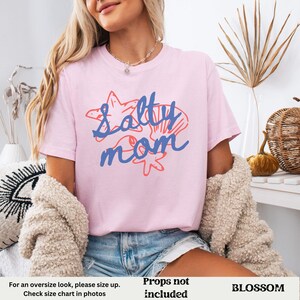 May include: Pink t-shirt with the text "Salty Mom" in blue and red. The text is surrounded by images of seashells and starfish.