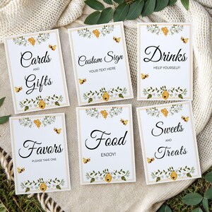 May include: Set of six white rectangular signs with black calligraphy text and bee-themed floral borders. The signs read "Cards and Gifts", "Custom Sign", "Drinks", "Favors", "Food", and "Sweets and Treats".