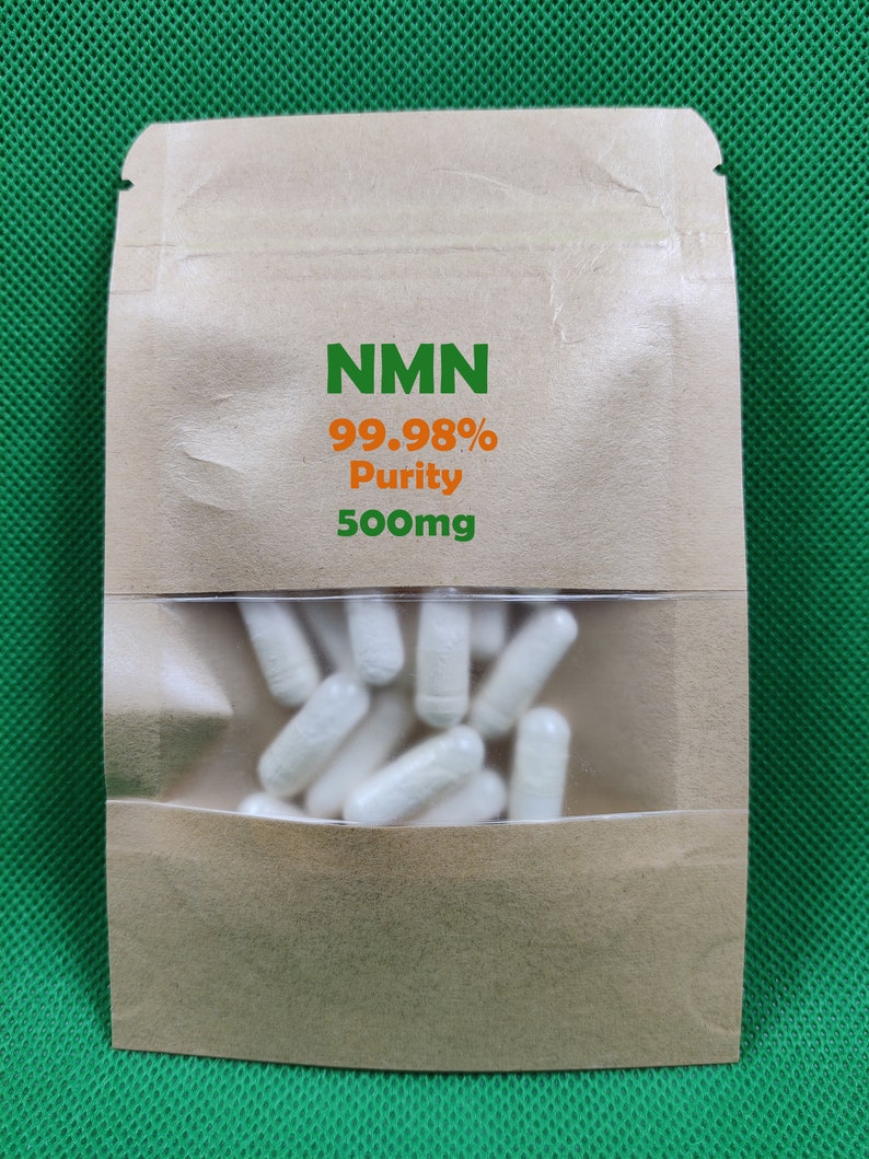 K&ouml;nnte beinhalten: Ein brauner Papierbeutel mit einem transparenten Fenster, in dem wei&szlig;e Kapseln zu sehen sind. Auf dem Beutel steht "NMN 99,98 % Reinheit 500 mg".