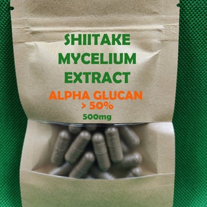 May include: A brown paper bag with a clear window showing a large quantity of brown capsules. The bag has the text "Shiitake Mycelium Extract Alpha Glucan >50% 500mg" printed on it.
