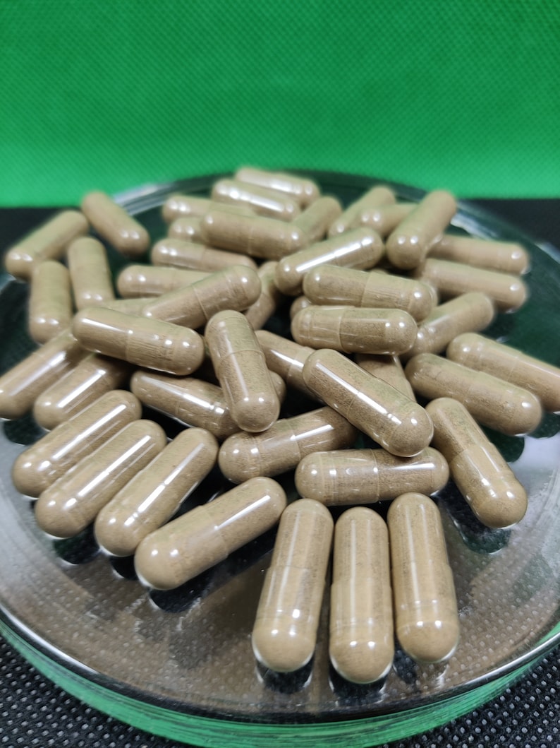 May include: A close-up image of a pile of brown capsules in a clear glass dish. The capsules are translucent and show the brown powder inside.
