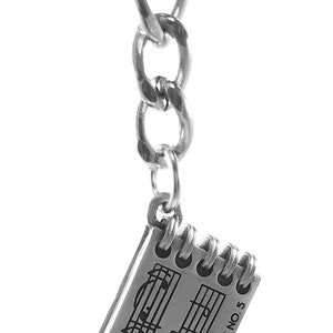 May include: A silver charm keychain featuring a small notebook with musical notes and the text "HUNGARIAN DANCE NO. 5".