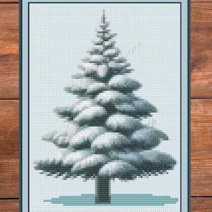 Op de afbeelding: Kruissteekkunst van een met sneeuw bedekte dennenboom in een lijst. De boom is weergegeven in tinten groen en wit, met een lichtblauwe achtergrond. De lijst is donkerblauw. De tekst "PDF Download" staat onderaan.