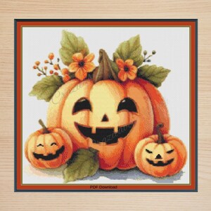 May include: Cross-stitch design of a smiling orange pumpkin with a carved face, and two smaller pumpkins. Green leaves and orange flowers decorate the top. The words "PDF Download" are at the bottom.