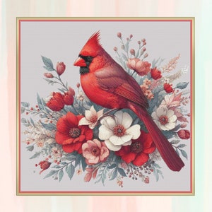 May include: A vibrant cross-stitch design featuring a red cardinal bird perched amidst a bouquet of red, white, and pink flowers. The bird has a prominent crest and black facial markings. The floral arrangement includes various blooms and foliage, set against a light gray background.
