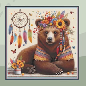 May include: A brown bear wearing a colorful flower crown and beaded necklace. The bear is sitting on a wooden surface with a dreamcatcher and flowers in the background.