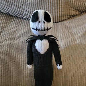 Könnte beinhalten: Eine gehäkelte Jack Skellington Puppe mit einem schwarz-weiß gestreiften Anzug und einem weißen Herzen auf der Brust. Die Puppe hat eine schwarze Fliege und einen schwarz-weiß gestreiften Hut.