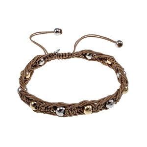 Op de afbeelding: Een macramé armband met een geweven bruin koordontwerp. De armband is versierd met een mix van zilver- en goudkleurige kralen. Verstelbare sluiting met twee zilveren kralen aan de uiteinden.