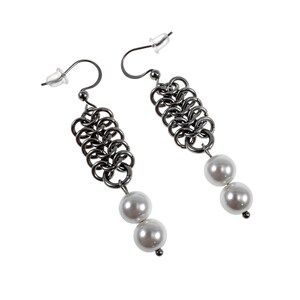 May include: A pair of dangle earrings with a chainmail design in a dark gunmetal colour. Each earring has two white, round faux pearls suspended from the chainmail. The earrings have a post and hook closure.