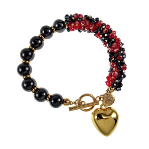 May include: A gold bracelet with a toggle clasp and a heart charm. The bracelet has black beads and a section of red and black crystal beads. The heart charm is a polished gold colour.