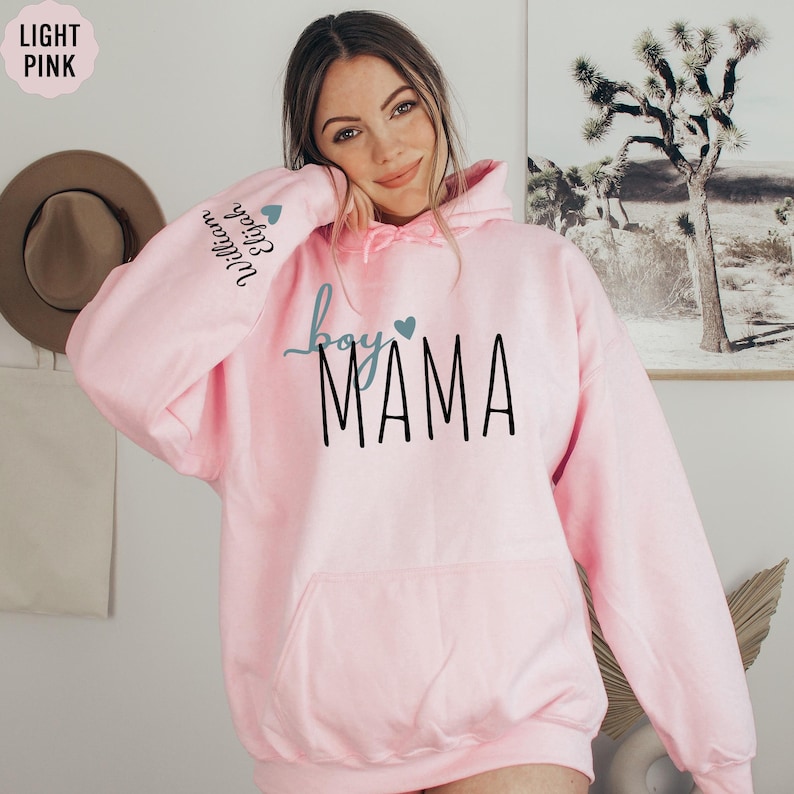 a woman wearing a pink hoodie with the word mama on it