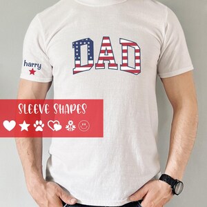 May include: A white short-sleeved t-shirt featuring the word DAD in a red, white, and blue American flag pattern. The sleeve displays the name harry above a red star. A red graphic overlay shows the text SLEEVE SHAPES with heart, star, paw, heart, flower, and smiley face icons.