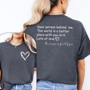 a woman wearing a t - shirt that says dear person behind me the world is