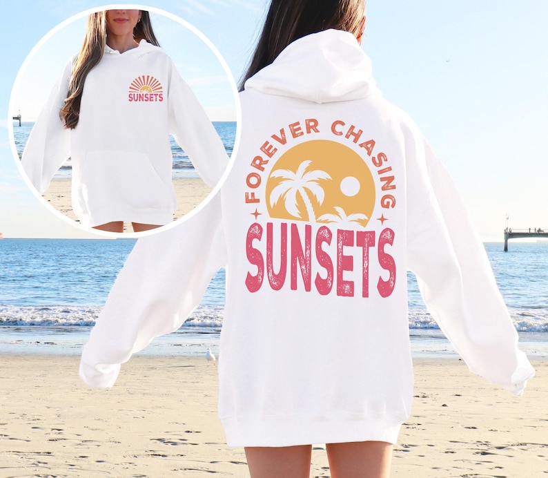 a woman standing on a beach wearing a white sweatshirt