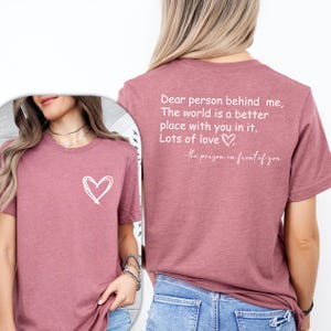 a woman wearing a t - shirt that says dear person behind me, the world