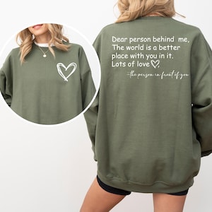 a woman wearing a green sweatshirt with a heart on it