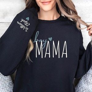 a woman wearing a black sweatshirt with the word mama printed on it