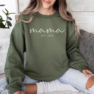 a woman sitting on a couch wearing a green sweatshirt