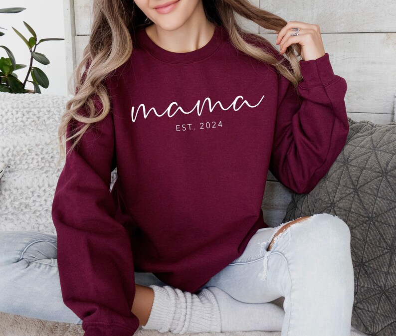 a woman sitting on a couch wearing a maroon sweatshirt