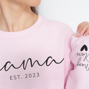 a woman wearing a pink sweatshirt with the word mama printed on it