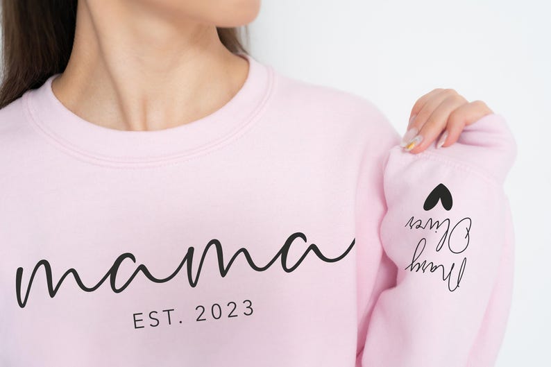 a woman wearing a pink sweatshirt with the word mama printed on it