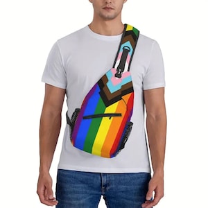 May include: A crossbody sling bag featuring a vibrant rainbow striped pattern across the main body and shoulder strap, accented with a chevron-shaped Progress Pride flag design at the top, a black zippered front pocket, and black mesh side pockets.