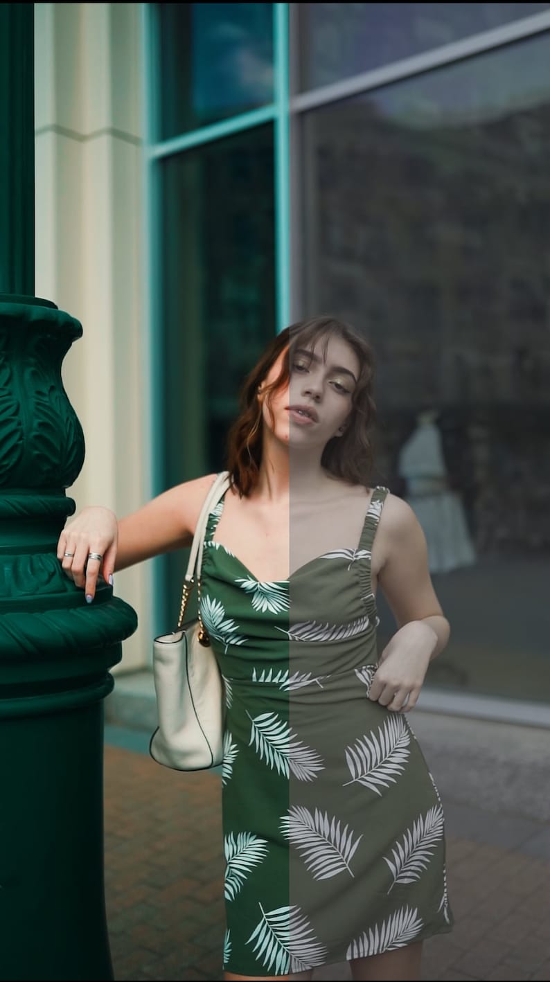 May include: A woman wearing a green and white tropical print dress with a white handbag. She is standing in front of a building with large windows.