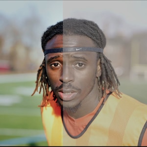May include: A close-up of a man's face, split in half, showing a color image on the left and a black and white image on the right. He is wearing a black headband with a white logo, a yellow and orange vest, and a red shirt. He has dreadlocks and is looking directly at the camera.