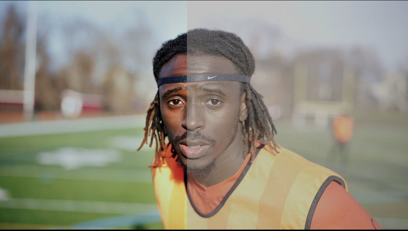 May include: A close-up of a man's face, split in half, showing a color image on the left and a black and white image on the right. He is wearing a black headband with a white logo, a yellow and orange vest, and a red shirt. He has dreadlocks and is looking directly at the camera.