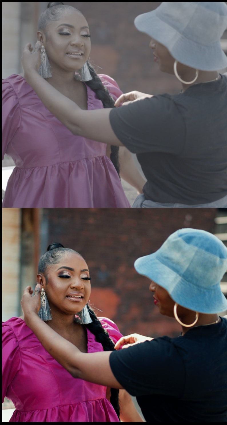 May include: Two women, one wearing a pink dress and the other wearing a black shirt and a blue hat, are adjusting each other's earrings. The woman in the pink dress has her hair pulled back in a ponytail.