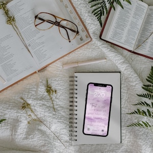 Pu&ograve; includere: Un taccuino bianco con rilegatura a spirale e uno sfondo acquerellato rosa e bianco. Uno smartphone con uno schermo di blocco che mostra l'ora 2:20 e un versetto biblico &egrave; sopra il taccuino. Il versetto dice "Confida nel Signore con tutto il tuo cuore; non fare affidamento sul tuo intelletto. Proverbi 3:5".
