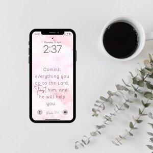 Pu&ograve; includere: Uno sfondo acquerellato rosa e bianco con una citazione sullo schermo di uno smartphone. La citazione recita "Affida al Signore tutto ci&ograve; che fai. Fidati di lui, e lui ti aiuter&agrave;." La citazione &egrave; attribuita al Salmo 37:5.