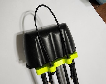 Puede incluir: Carcaj de tiro con arco negro con base verde neón y asa de cuerda negra. El carcaj está diseñado para guardar flechas, con varias flechas visibles. El carcaj está hecho de un material texturizado.