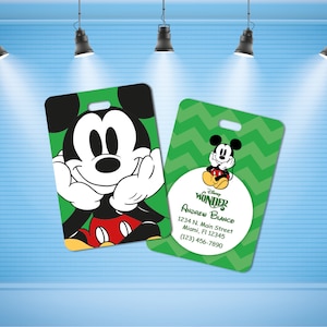 May include: Two green and white luggage tags with a Mickey Mouse cartoon character. One tag features a close-up of Mickey Mouse's face and the other tag features a smaller image of Mickey Mouse sitting down. The text on the tag reads "Disney Wonder, Andrew Blance, 1234 N. Main Street, Miami, FI 12345, (123) 456-7890."