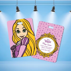 May include: Two pink luggage tags. One features a cartoon of a blonde woman in a purple dress. The other tag has a pink star pattern with a gold frame and the text "Disney Wish" and contact information.