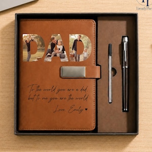 May include: A brown leather journal with the word "DAD" cut out, revealing family photos. The journal includes a metal clasp and the inscription "To the world you are a dad, but to me you are the world. Love, Emily." A pen and refill are included.