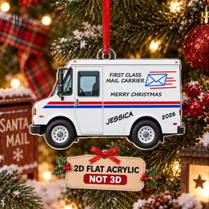 May include: A white mail truck Christmas ornament featuring a red and blue stripe, the text FIRST CLASS MAIL CARRIER, MERRY CHRISTMAS, JESSICA, and 2026. A small tan tag attached below reads 2D FLAT ACRYLIC NOT 3D with a red bow and holly.